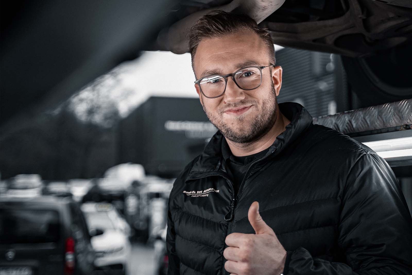 Monteur steht unter Auto auf Hebebühne von Nord-Ostsee Automobile